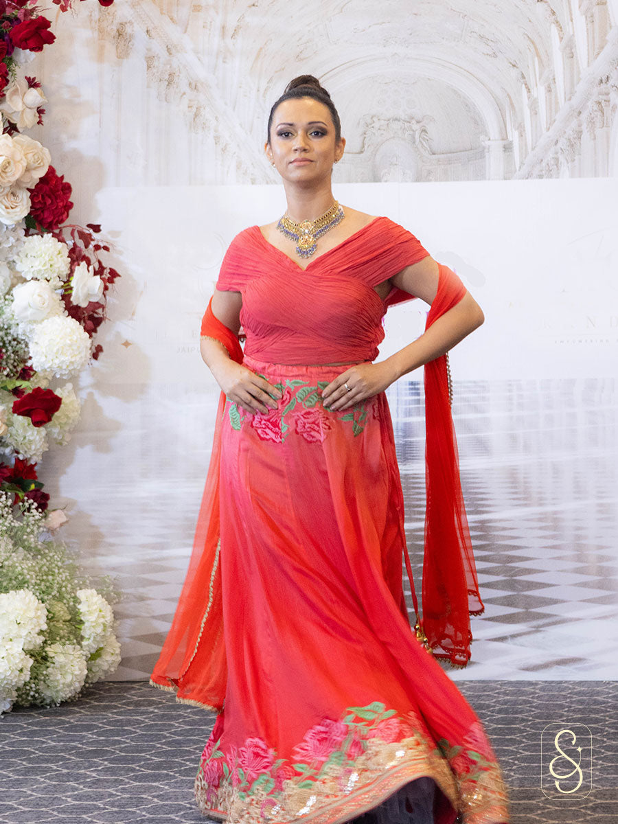 A woman in a soft silk red lehenga with ruched blouse.