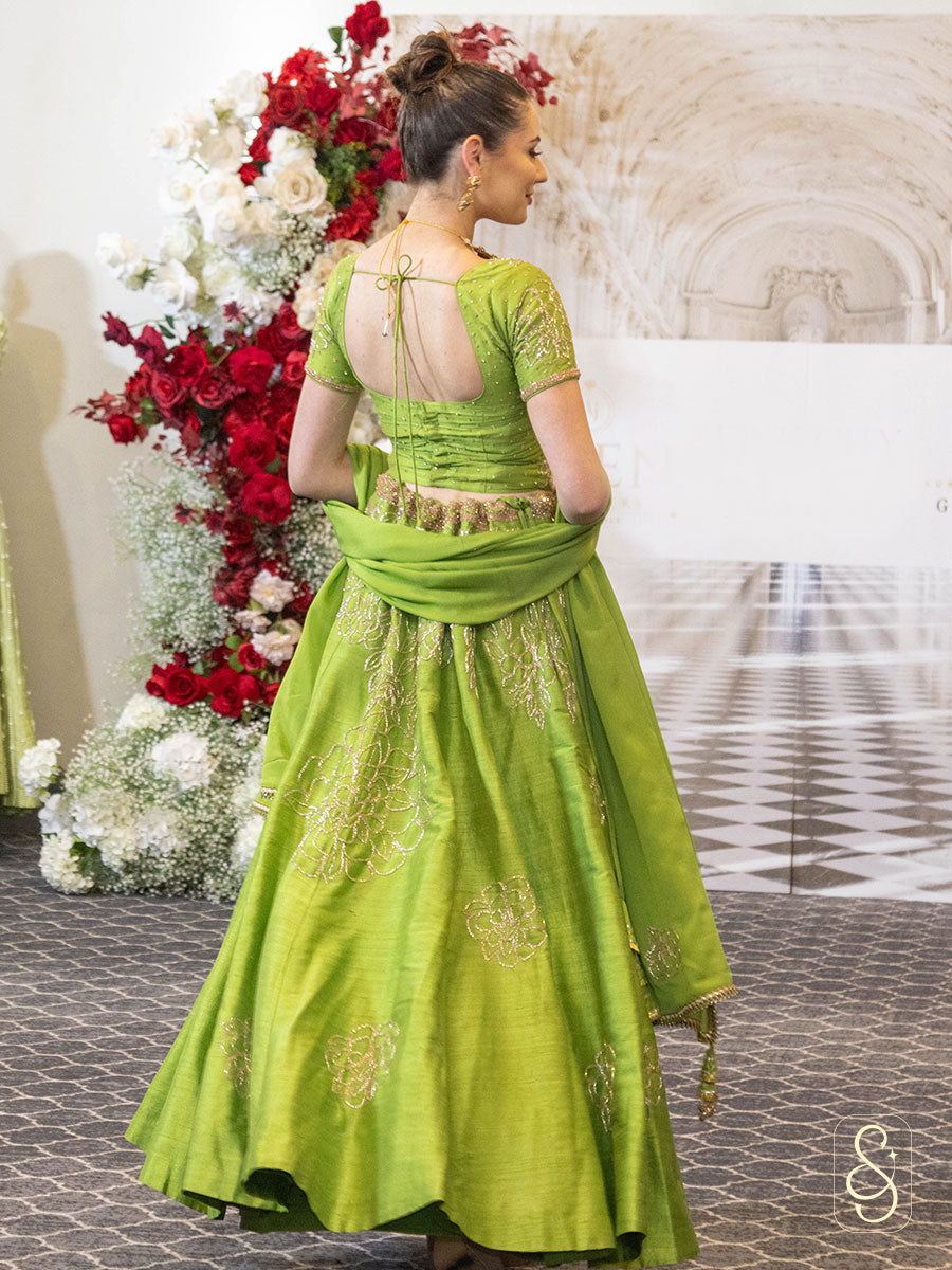 A woman in a light green coloured silk lehenga with matching blouse and chinon dupatta, decorated with bugle beads embroidery.