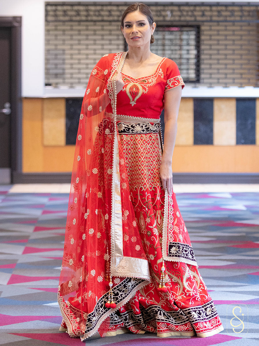 Woman wearing a red traditional lehenga with intricate embroidery patterns.