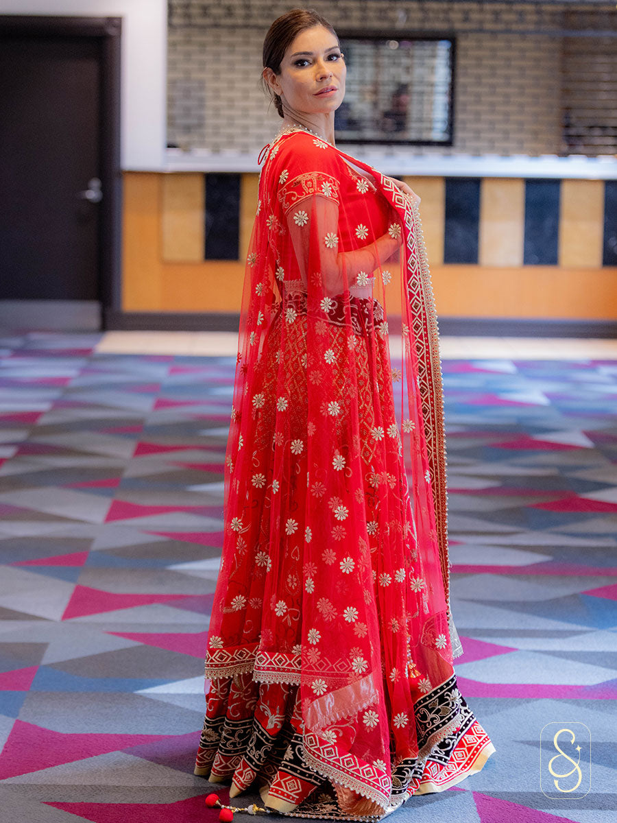 Right side view of a woman in a red traditional lehenga choli with floral zardozi embroidered patterns.