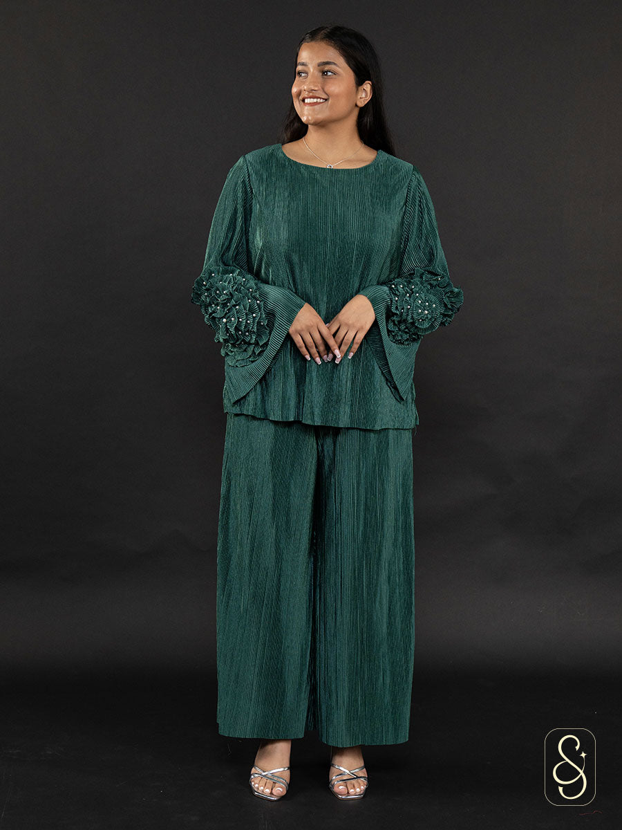 Woman wearing a soft satin wrinkled green fabric co-ord set with embellished sleeves.