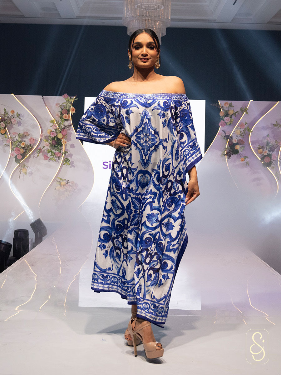 Woman posing on a ramp show wearing a blue and white patterned kaftan.