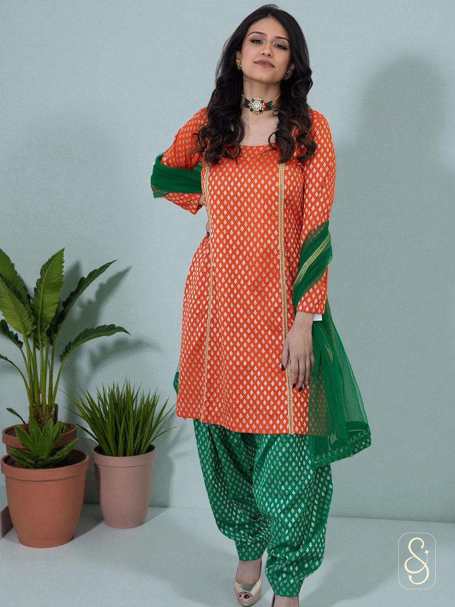 Woman wearing an orange and green brocade salwar suit with green organza dupatta.