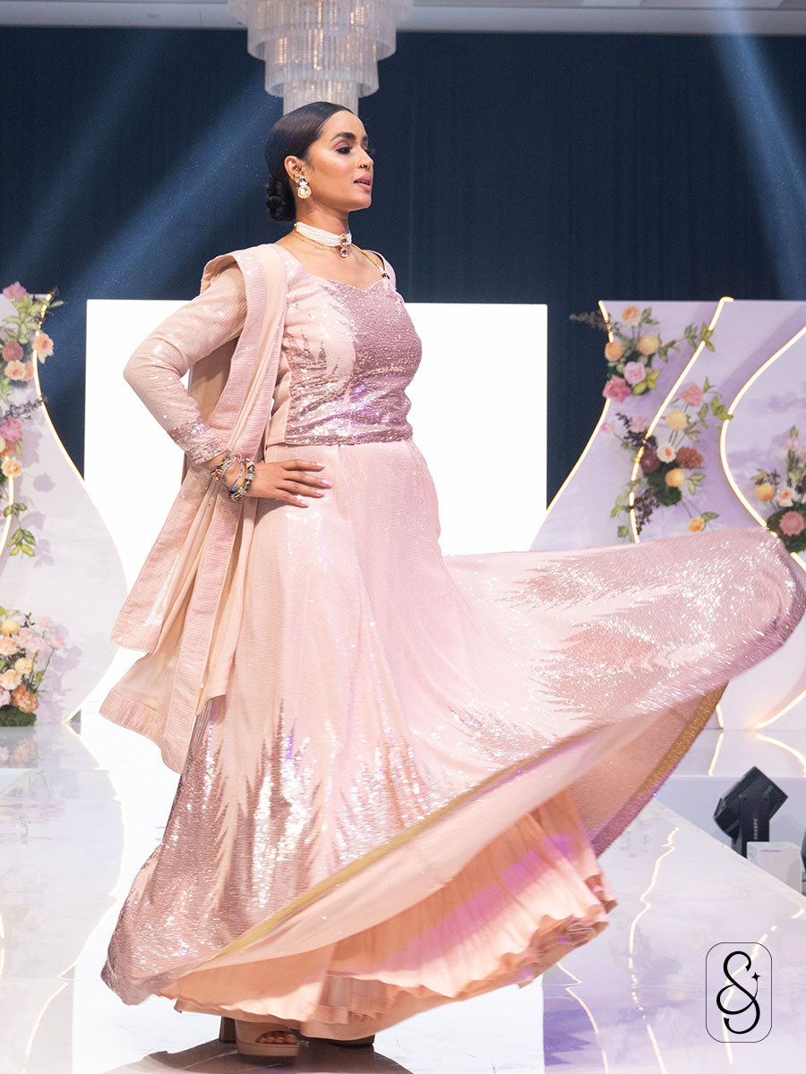 Woman twirling on a stage by wearing a pink sequin lehenga with matching blouse and dupatta.