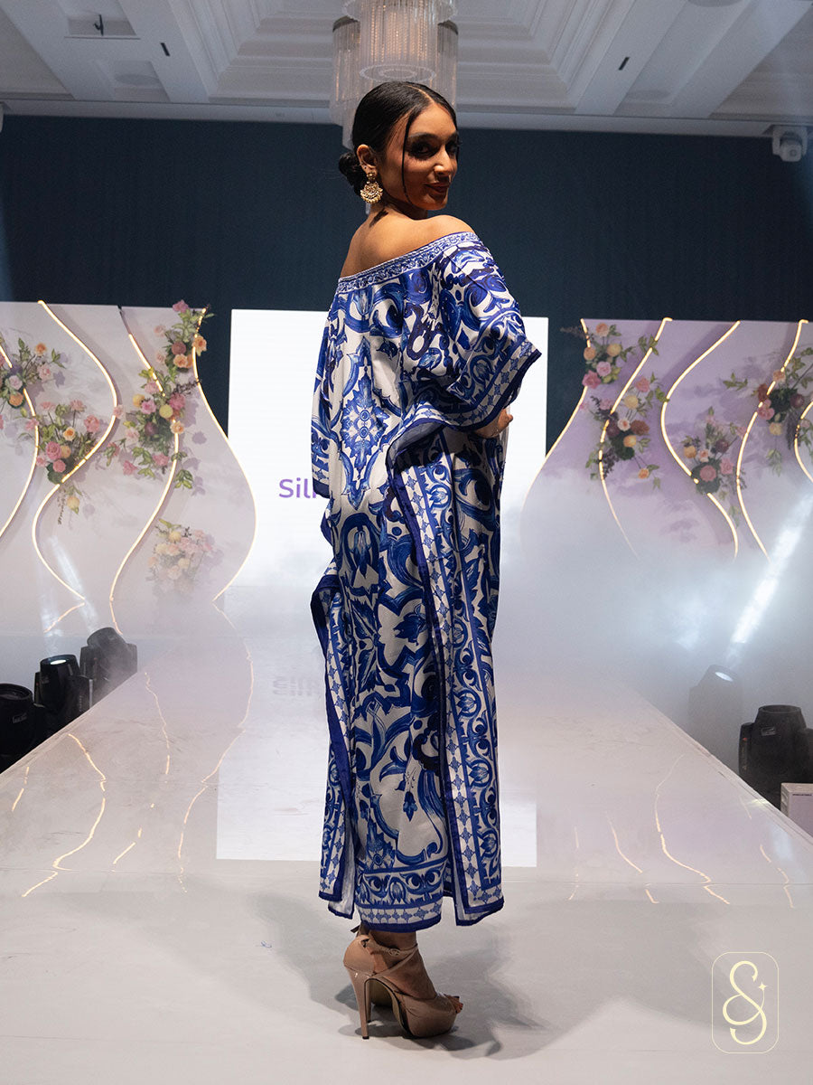Woman posing on a ramp show wearing a blue and white patterned kaftan.