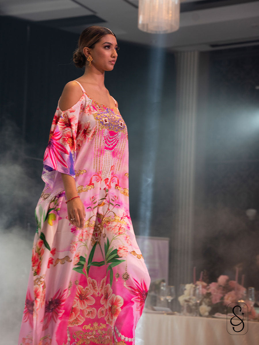 A side view of a model wearing a pink floral printed kaftan.
