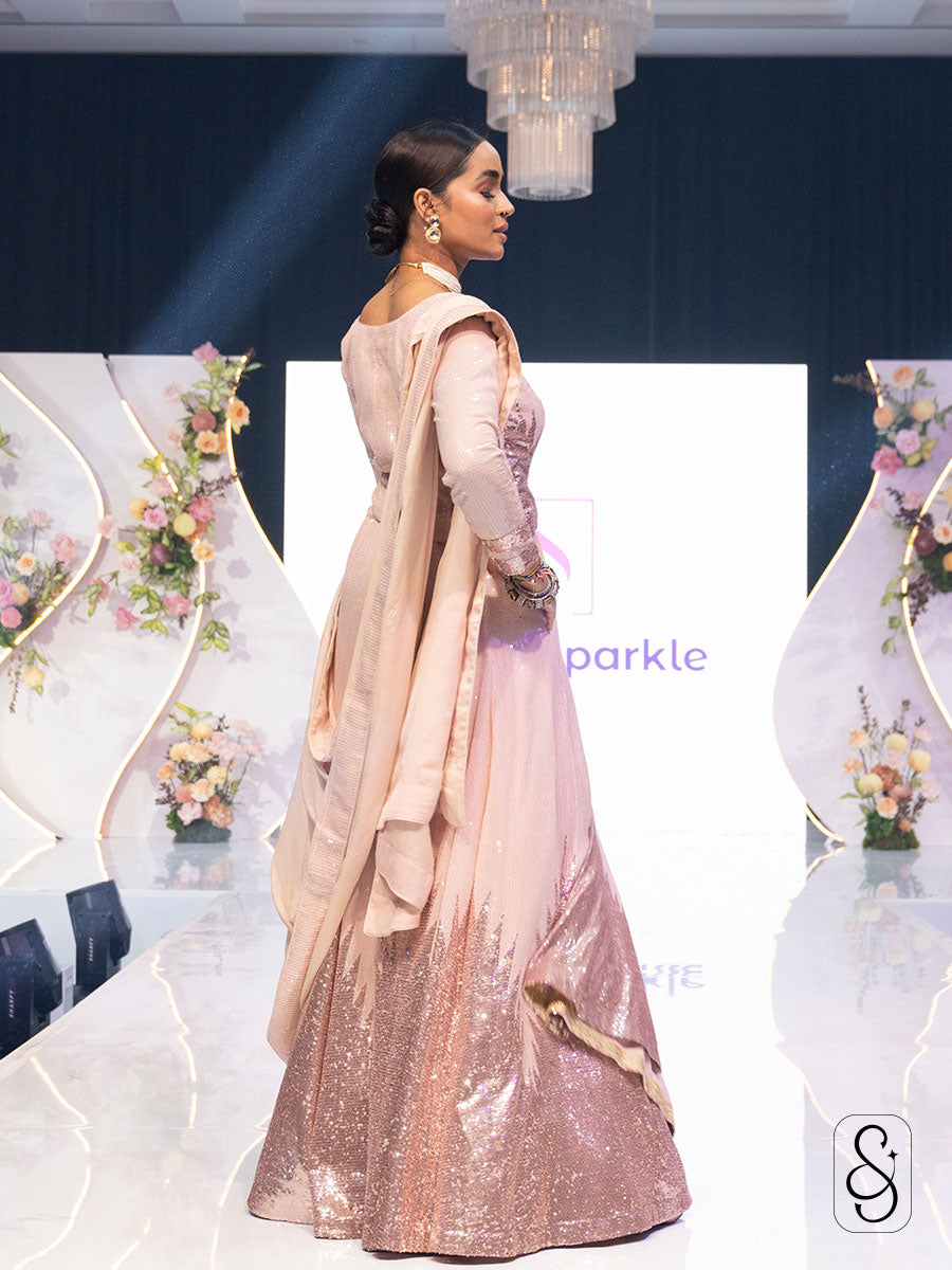 Side view of a woman wearing a soft pink sequin work lehenga set.