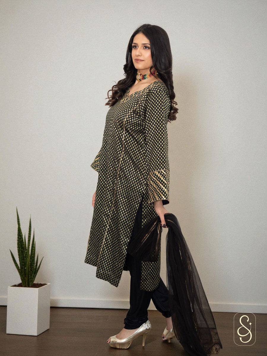 Woman wearing a long, patterned black and golden colour suit.