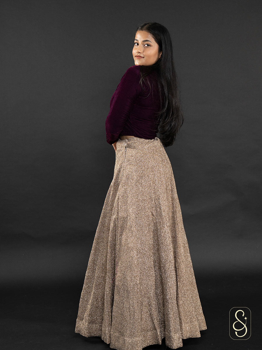 A woman wearing a lurex crushed tissue lehenga and dupatta pair with a purple velvet blouse.