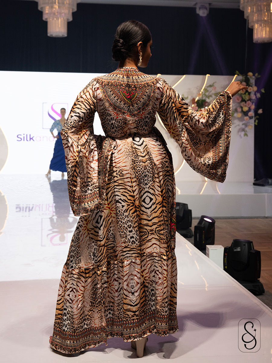 Woman showing the back design of a patterned dress on a runway.