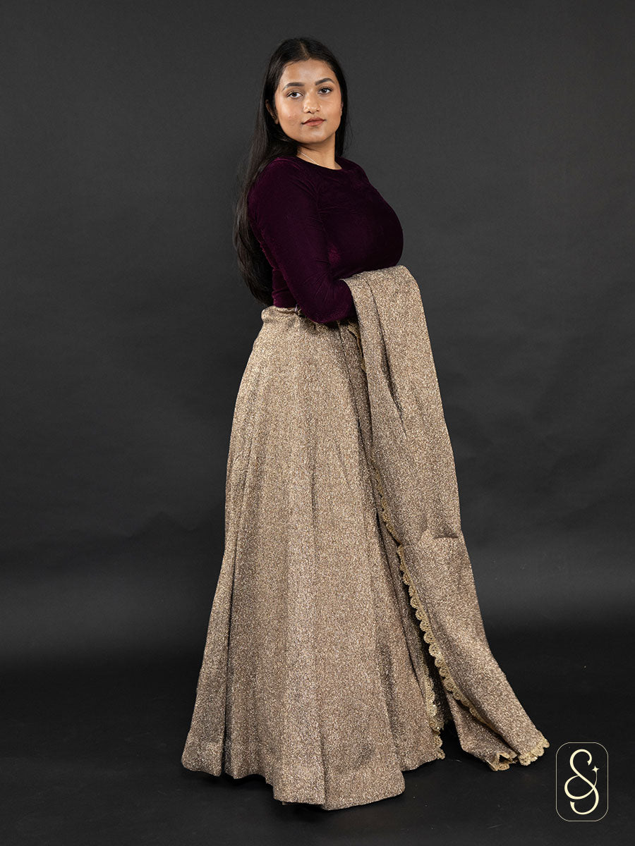 A woman wearing a lurex crushed tissue lehenga and dupatta pair with a purple velvet blouse.
