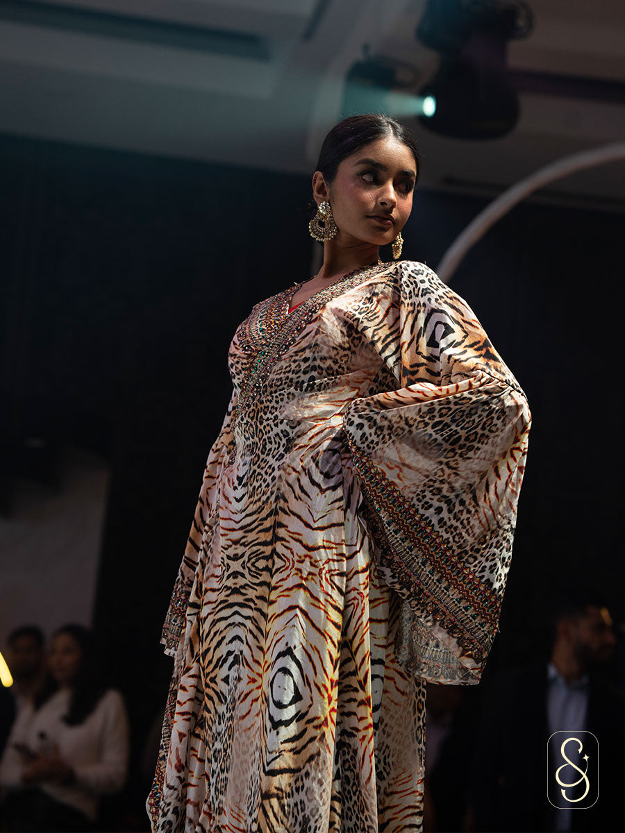 Model wearing a leopard print wrap dress on a fashion show runway.