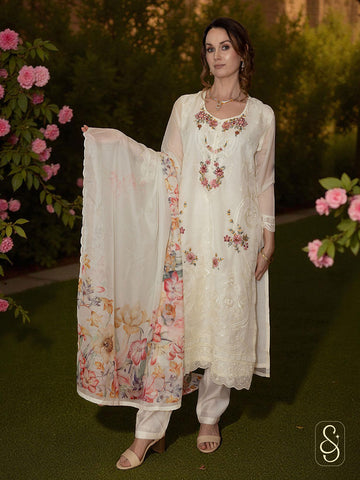 Woman wearing a floral embroidered white suit set with a matching dupatta in a garden setting.