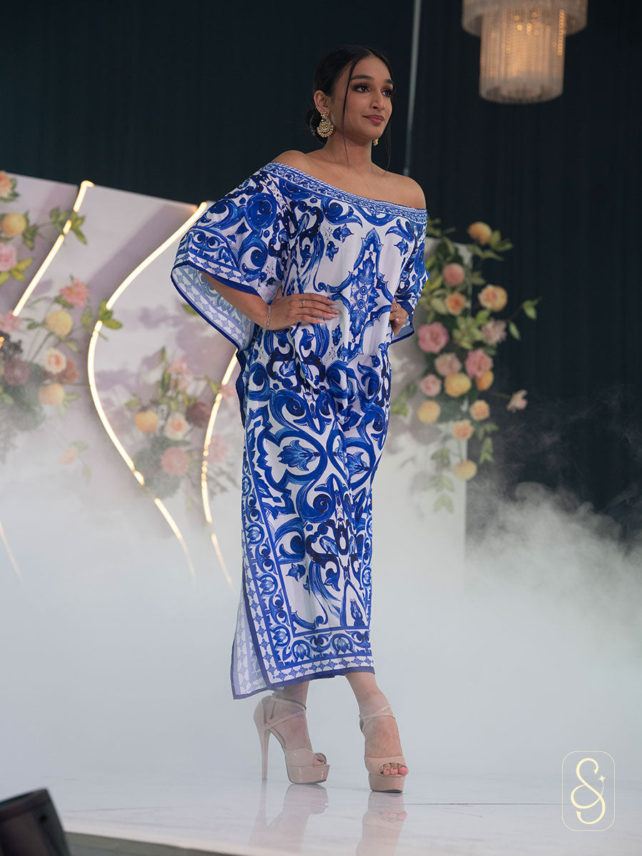 Model wearing a blue and white patterned off-shoulder kaftan with a high heel.