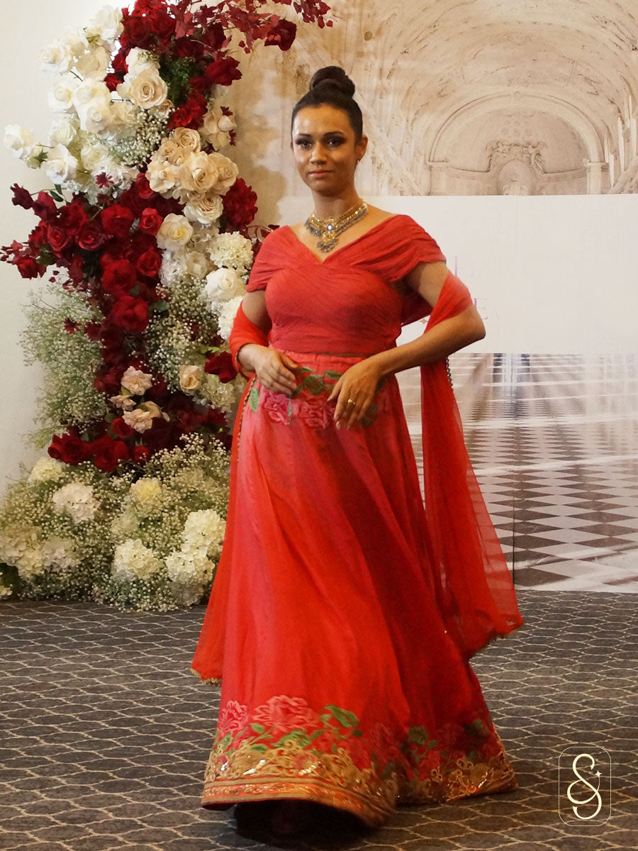 A woman walks on the ramp show by wearing a soft silk embroidered lehenga with ruched blouse. 