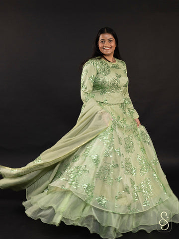 Woman wearing a light green shimmering sequin embroidered lehenga with organza dupatta.