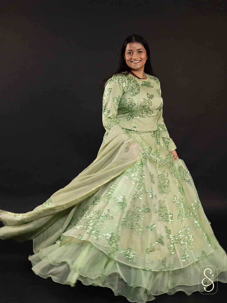 Woman wearing a light green shimmering sequin embroidered lehenga with organza dupatta.
