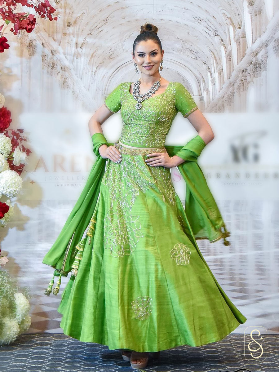 A woman in a light green coloured silk lehenga with matching blouse and chinon dupatta, decorated with bugle beads embroidery.